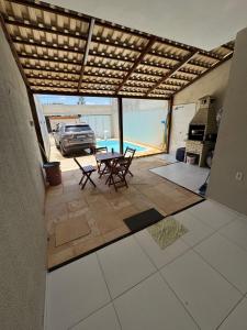 eine Terrasse mit einem Tisch und Stühlen sowie einem Auto in der Unterkunft Casa com piscina privativa em paracuru in Paracuru