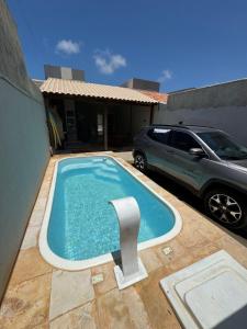 ein Schwimmbad vor einem Haus mit Auto in der Unterkunft Casa com piscina privativa em paracuru in Paracuru