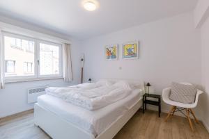 une chambre blanche avec un lit et une chaise dans l'établissement La Bohème Koksijde, à Coxyde