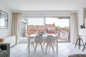 a white dining room with a white table and chairs at La Bohème Koksijde in Koksijde