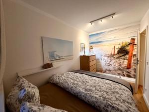 una camera con letto e una foto di una spiaggia di Frische Brise 704 a Sahlenburg Altre 11 foto