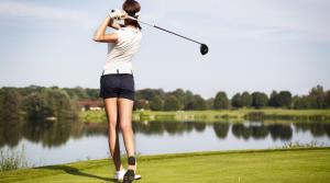 une femme balançant un club de golf en face d'un lac dans l'établissement VILLA AM SEE - nähe Berlin, à Biesenthal