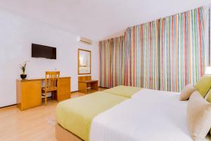 a bedroom with a bed and a desk and a television at Monica Isabel Beach Club in Albufeira