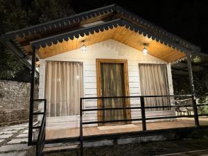 a small white house with a porch at night at The Hilltop Hideaway in Mukteshwar