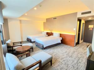 a hotel room with two beds and a couch at Hotel Keihan Sapporo in Sapporo