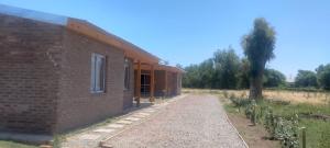 a brick building with a pathway next to a tree at Casa 2 Dormitorios, Barrio El Calden in Carhué