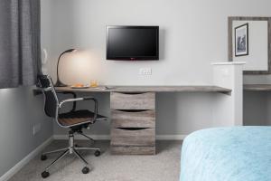 ein Schlafzimmer mit einem Schreibtisch mit Fernseher und einem Stuhl in der Unterkunft The Willows Training Centre in Saint Neots