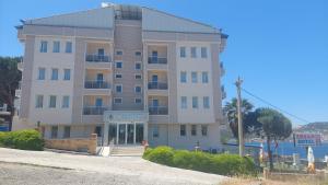 a large apartment building on the side of a beach at erşan hotel in Foça