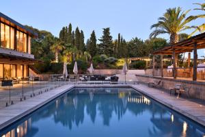 a pool at a resort with chairs and umbrellas at La Réserve Esterel in Saint-Raphaël