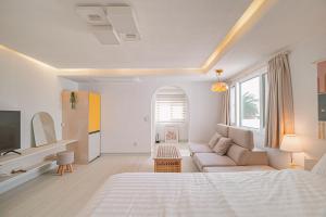 a white bedroom with a large bed and a couch at 레이니데이 in Namŭm-ni