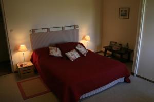 - une chambre avec un grand lit rouge et deux lampes dans l'établissement Le Moulin de Montrésor, à Montrésor