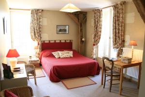 - une chambre avec un lit rouge, une table et des chaises dans l'établissement Le Moulin de Montrésor, à Montrésor