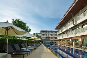 a pool with chairs and umbrellas next to a hotel at Srisuksant Resort in Ao Nang Beach