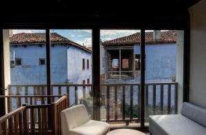 Zimmer mit einem Balkon mit einem Stuhl und Fenstern in der Unterkunft Αρχοντικό Παπαγιάννη in Edessa