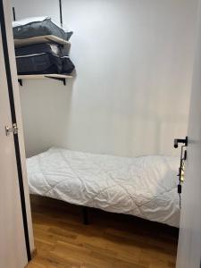 ein Bett in einem Zimmer mit einer weißen Wand in der Unterkunft Appartement agréable à deux pas du plan d'eau in Embrun