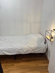 ein Bett in einem Zimmer mit einer weißen Wand in der Unterkunft Appartement agréable à deux pas du plan d'eau in Embrun