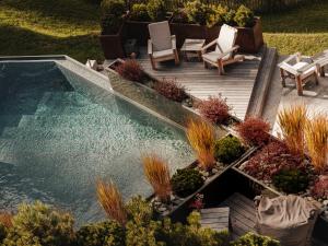 een zwembad in een tuin met stoelen en planten bij OVERLOOK Lodge by CERVO Zermatt in Zermatt
