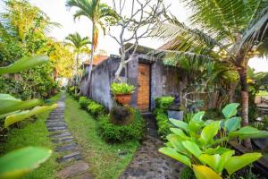 a garden with palm trees and a building at Asri Sari Ubud Resort in Ubud