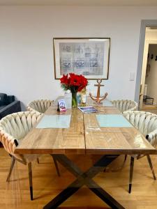 a wooden table with a vase of red flowers on it at Sylter Seestern App Ankerplatz in Morsum