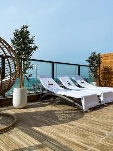 two lounge chairs on a balcony with a view of the ocean at מלון ארנה בת ים - קומת סוויטות הגן עם סאונה פרטית in Bat Yam +9 photos