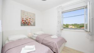 zwei Betten in einem weißen Zimmer mit Fenster in der Unterkunft Villa Ivan by Villas Guide in Primorski Dolac + 27 Fotos