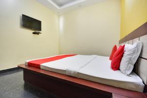 una camera da letto con un letto con cuscini rossi e bianchi di Hotel O Santosh Seva Sadan a Rāiwāla