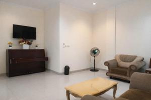 een woonkamer met een tv en een bank en een stoel bij Acrolia Homestay in Sentool