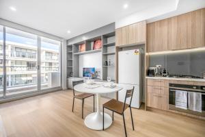 a kitchen with a white table and chairs in a room at Tranquil Studio in Schofields in Schofields