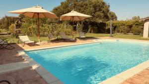 a swimming pool with two umbrellas and two chairs at Pool Villa With Animals Near Sutri in Sutri