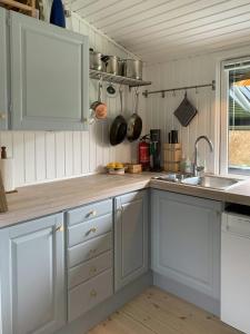 una cucina con mobili bianchi e un lavandino di Summer Bliss With Vibrant Garden In Nødebohuse a Kikhavn