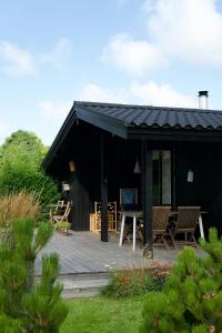 una cabina nera con un ponte di legno e sedie di Summer Bliss With Vibrant Garden In Nødebohuse a Kikhavn