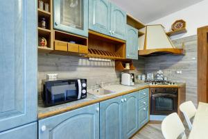 een keuken met blauwe kasten, een wastafel en een magnetron bij In Casetta da Mae in Lorenzago +22 foto's