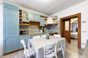 een keuken met blauwe kasten en een witte tafel en stoelen bij In Casetta da Mae in Lorenzago