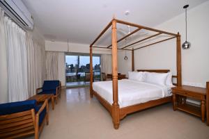 a bedroom with a four poster bed and a desk at Vedic Village Retreat Alleppey in Alleppey