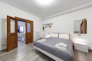 een witte slaapkamer met een bed en een houten vloer bij In Casetta da Mae in Lorenzago