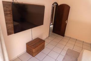 een woonkamer met een grote flatscreen-tv aan de muur bij Recanto aconchego in Peruíbe