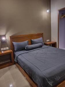 een slaapkamer met een bed met blauwe lakens en 2 tafels bij Kalih Homestay Bali in Kuta