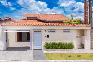 een huis met een witte garage en een rood dak bij Recanto aconchego in Peruíbe