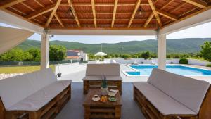 eine Terrasse mit 2 Stühlen, einem Tisch und einem Pool in der Unterkunft Holiday home Neda by Villas Guide in Primorski Dolac