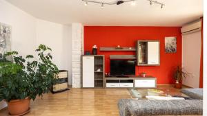 ein Wohnzimmer mit einer roten Wand und einem TV in der Unterkunft Holiday home Neda by Villas Guide in Primorski Dolac