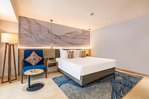een slaapkamer met een wit bed en een blauwe stoel bij Sterling Arka Suites, Puri in Puri +24 foto's