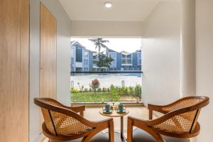 een kamer met twee stoelen, een tafel en een raam bij Sterling Arka Suites, Puri in Puri