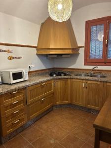 a kitchen with wooden cabinets and a microwave at Bike Cueva - Los Coloraos in Gorafe