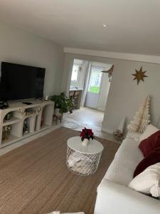 a living room with a white couch and a flat screen tv at Kaz Bohèm in Ambleteuse