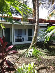 een wit huis met een palmboom ervoor bij Hotel Exotic Lodge in Puerto Viejo