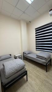 een kamer met 2 bedden en een raam erin bij Ugolok Xostel in Yakkasaray