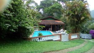 een huis met een zwembad en een prieel bij Sítio Refúgio Primavera in Monte Verde