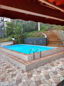 een zwembad met een trap en een parasol bij Sítio Refúgio Primavera in Monte Verde