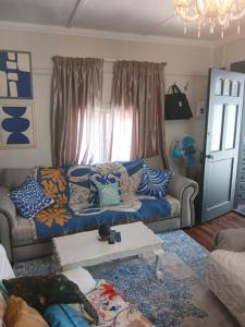 een woonkamer met een bank en een tafel bij Jann's Cozy Cottage in Bredasdorp
