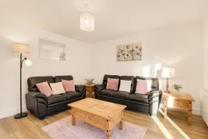 a living room with a black couch and a table at Yeavering - North East Escapes in Wooler